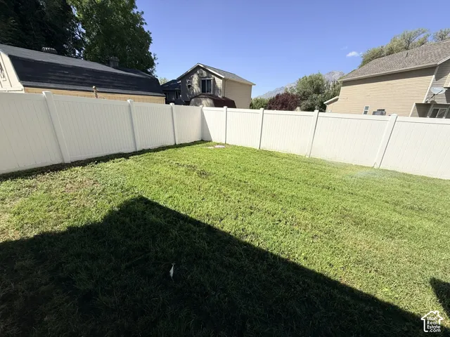 Expansive grassy area featuring a perimeter privacy fence