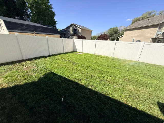 Expansive grassy area featuring a perimeter privacy fence