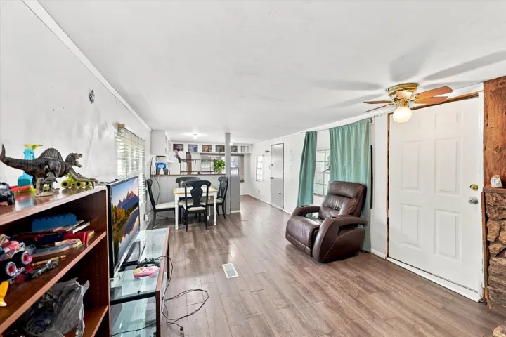 Open-concept living space featuring wood-finish flooring, a ceiling fan, and white paneled interior doors