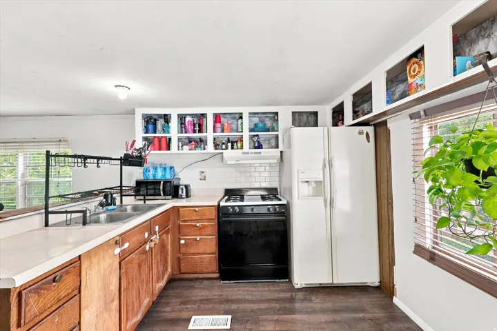 Kitchen with wood-finish flooring, white subway tile backsplash, and light-colored countertops