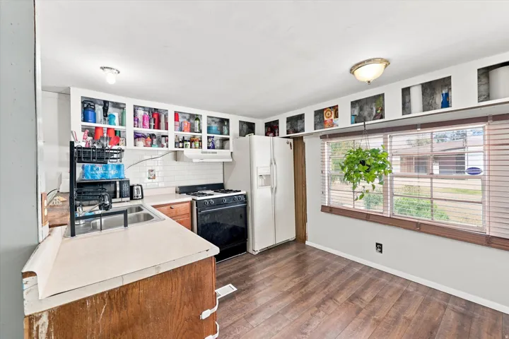 Wood-finish flooring, white subway tile backsplash, and a double basin sink