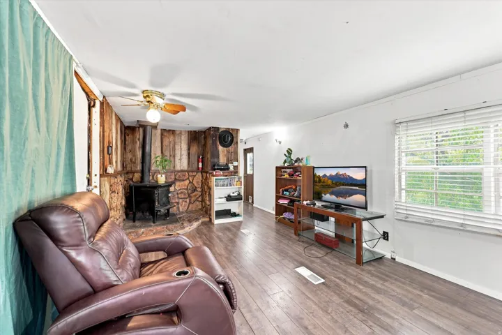 Wood-finish flooring, white walls, and a stone-clad accent wall with wood paneling