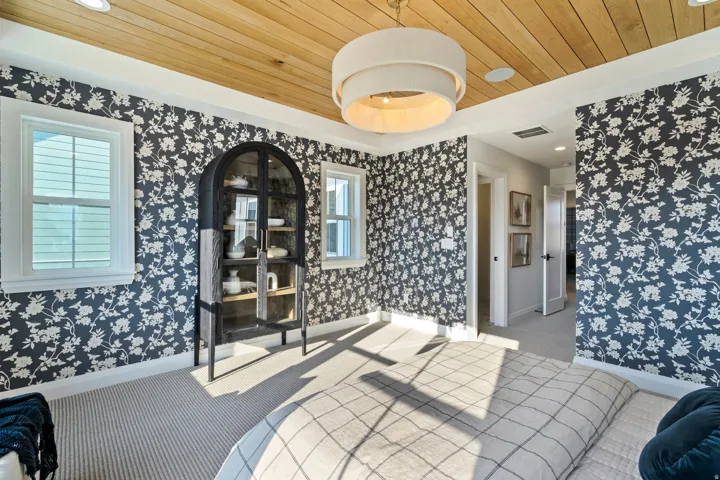 Wood-finish paneled ceiling, dual windows with white framing, recessed lighting, and a contemporary chandelier