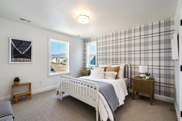 Carpeted room featuring a plaid accent wall, two windows, and a flush mount ceiling light fixture