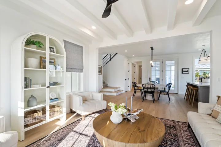 Open-concept living area featuring a coffered ceiling, wood-finish flooring, and white built-in shelving