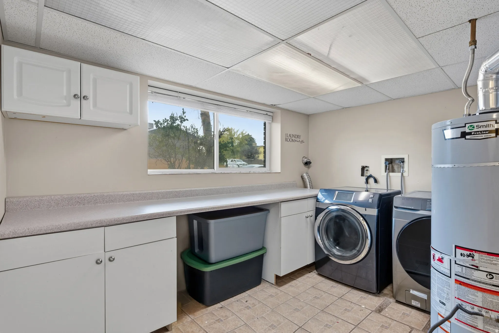 Integrated laundry area featuring white cabinetry, a long countertop, and tiled flooring