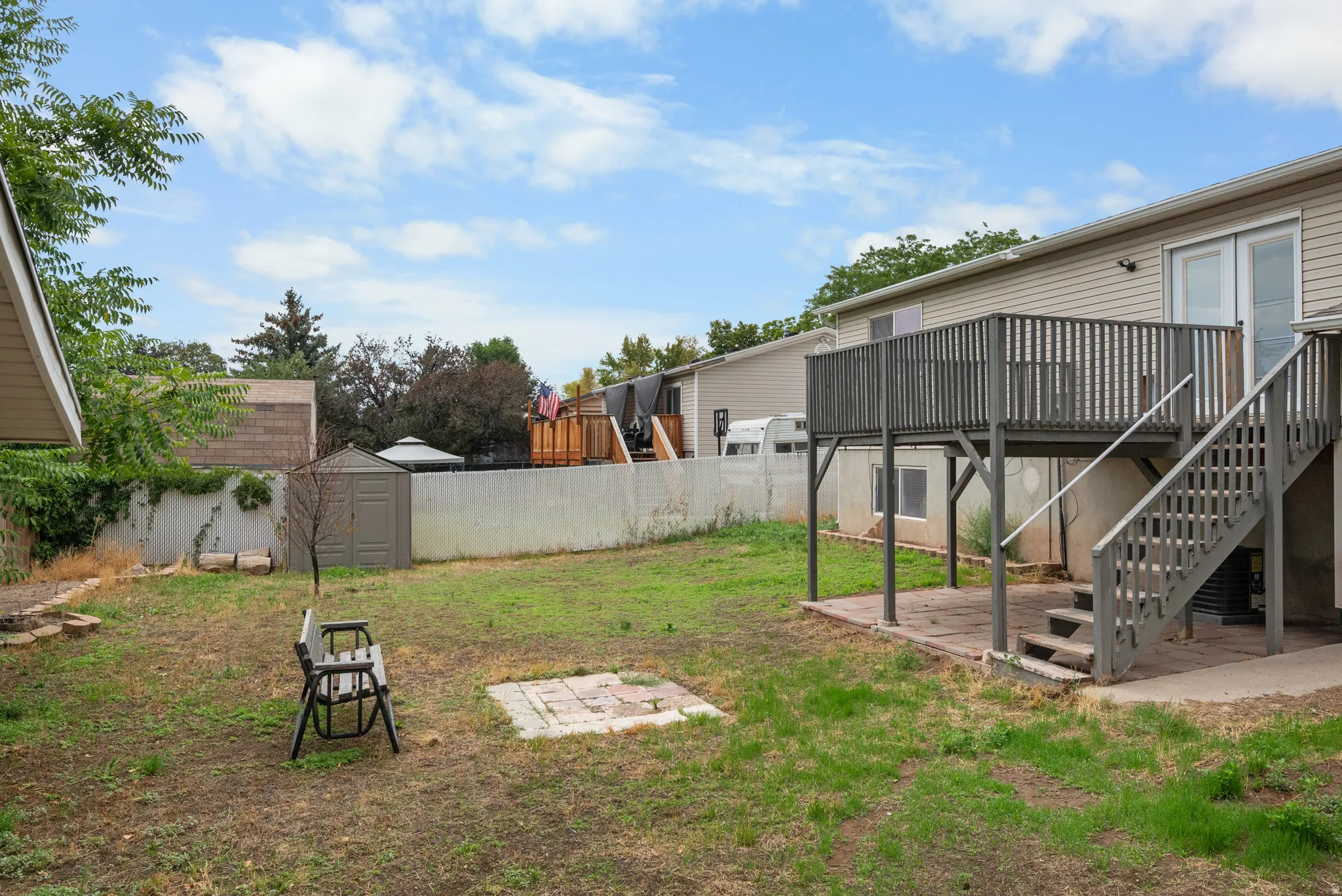 Raised wooden deck with stairs to ground level, featuring a sliding glass door entry