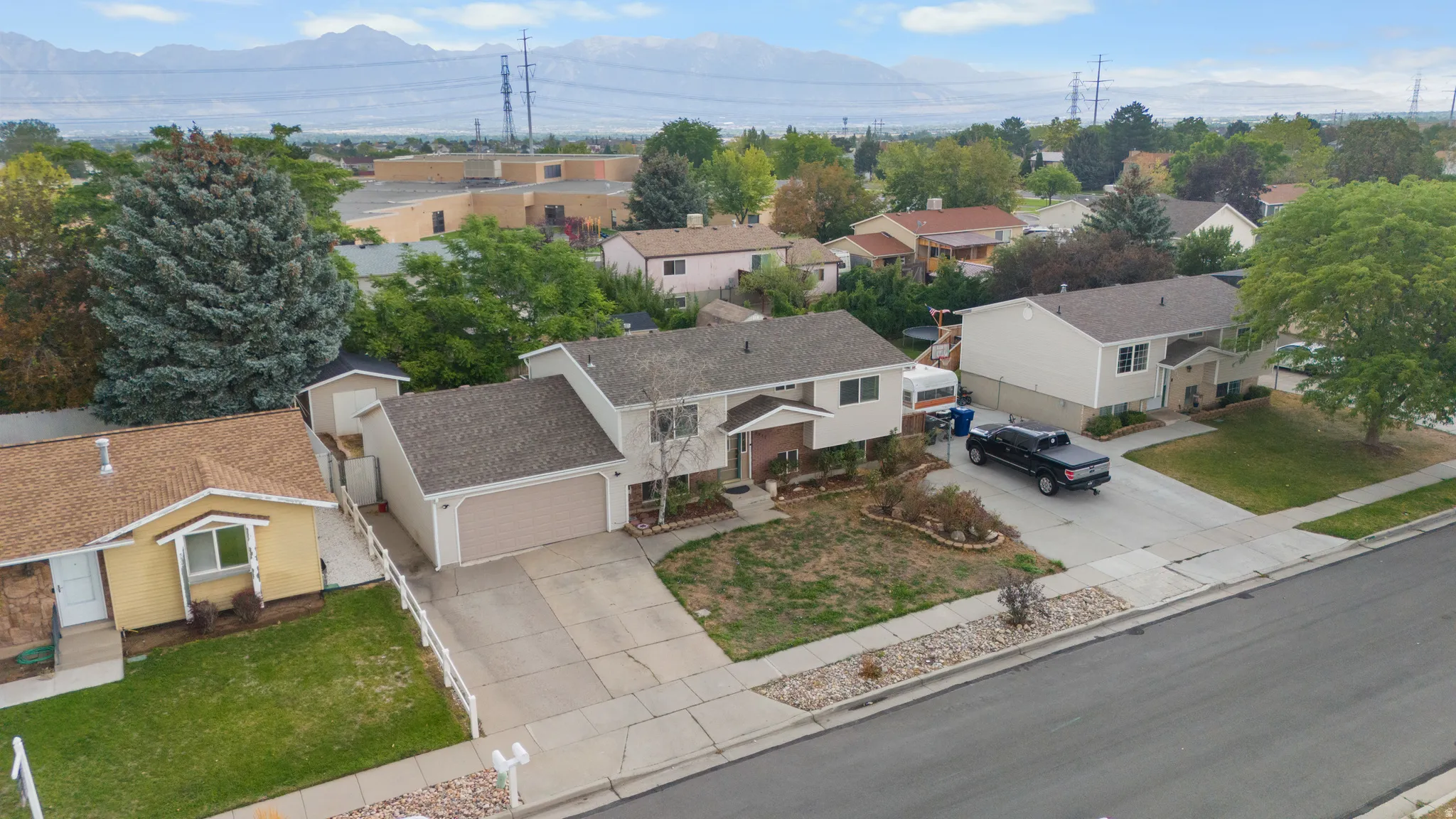 Two-story residence featuring an attached garage, paved driveway, and mature landscaping