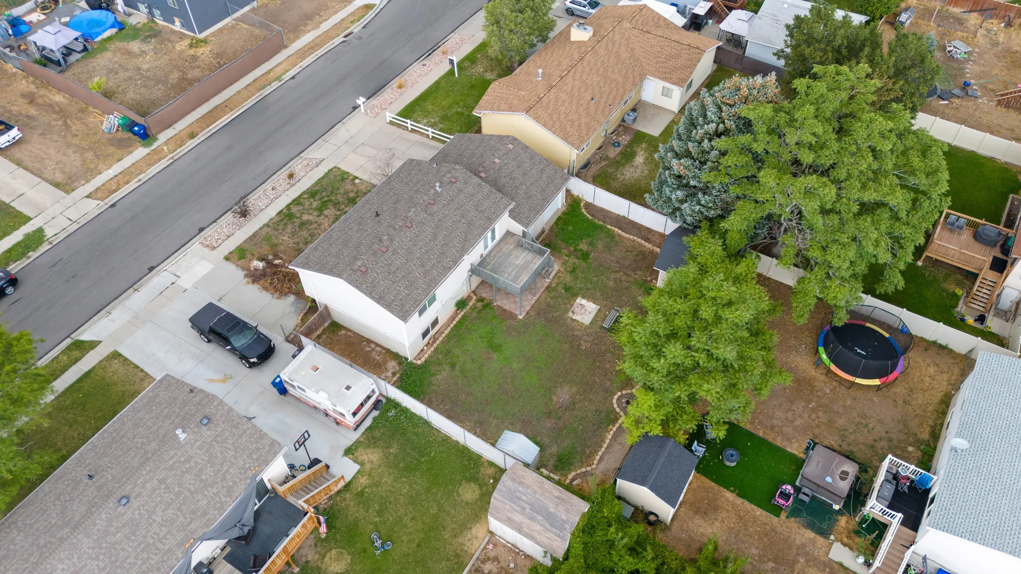 Expansive backyard featuring mature trees, a multi-level deck, and a detached storage shed