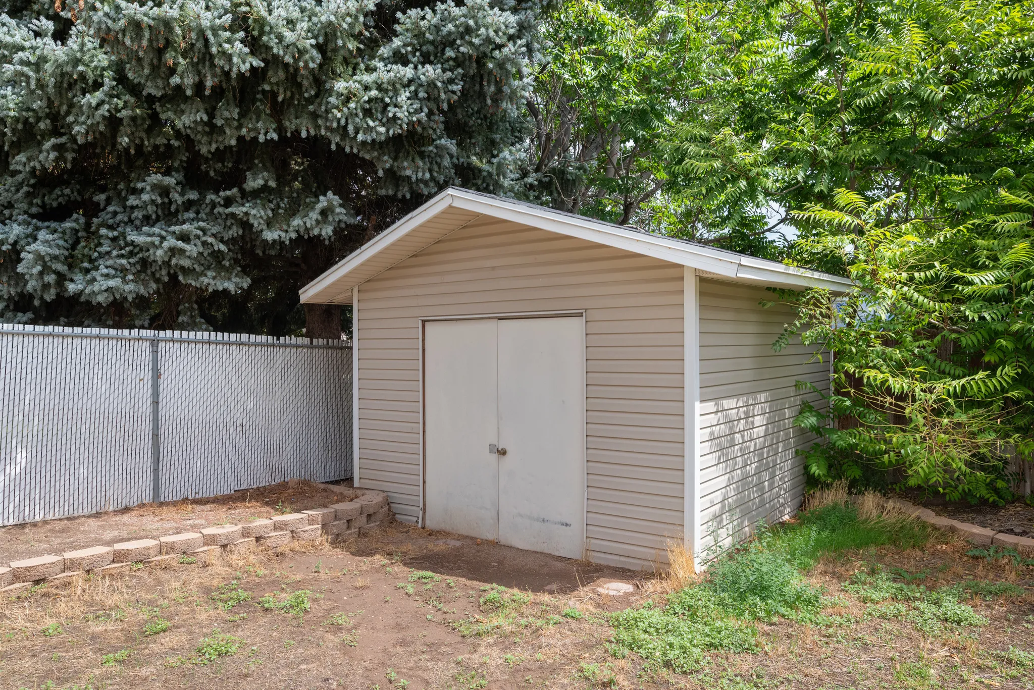 Utility shed with horizontal siding, a gabled roof, and double doors