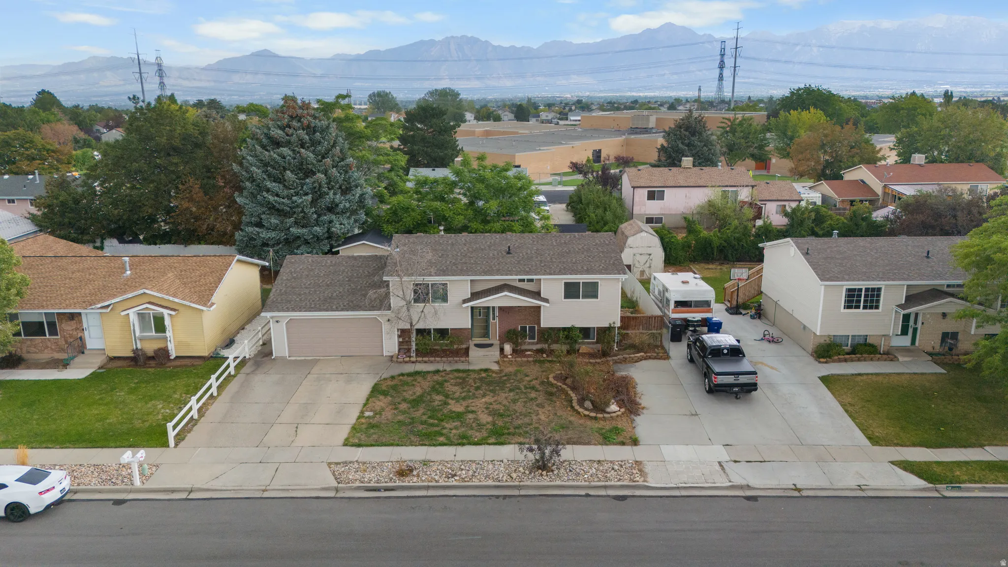 Two-story residence with an attached garage, paved driveway, and mature landscaping