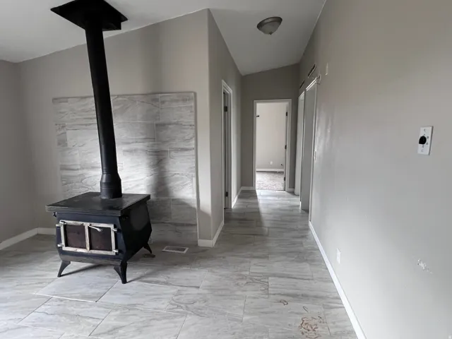 Wood-burning stove with a tiled backdrop, light gray wall color, and tile flooring