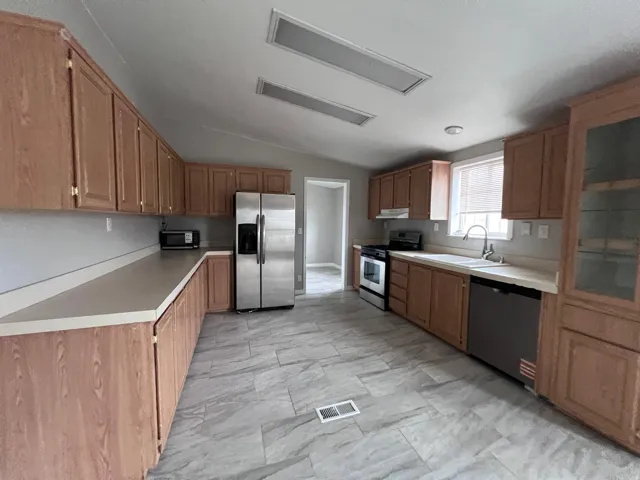 Kitchen featuring wood-finish cabinetry, light countertops, and tile flooring
