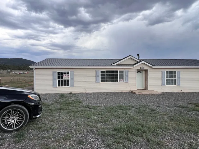 Light-colored horizontal siding with contrasting shutters and a dark metal roof