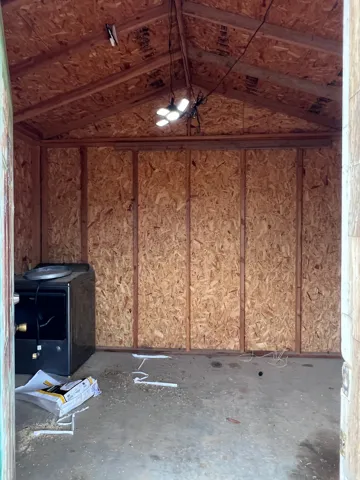 Interior storage structure with exposed wood framing, oriented strand board walls, and concrete flooring
