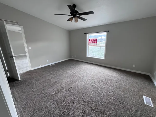 Neutral wall paint, ceiling fan with light kit, and durable carpet flooring