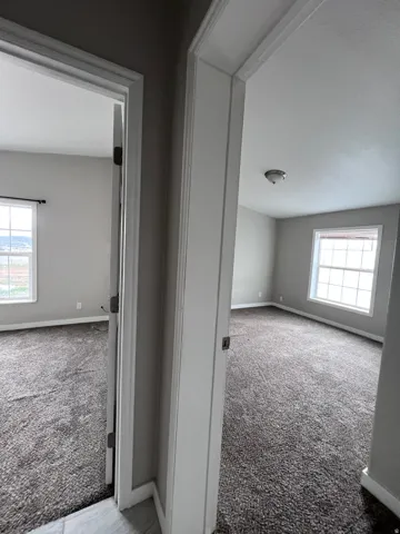 Two distinct rooms featuring neutral grey walls and dark grey textured carpeting