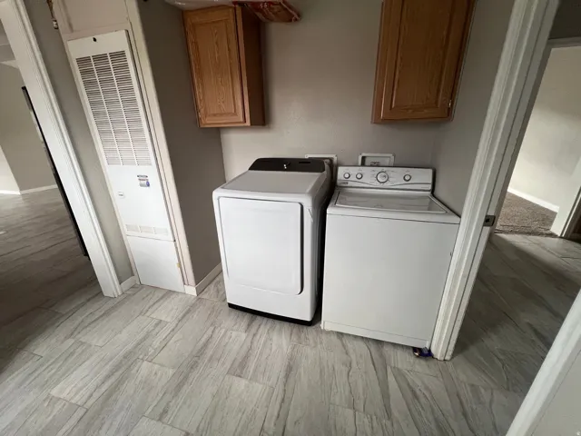 Wood-finish flooring with a wall-mounted furnace and overhead wood-finish cabinetry