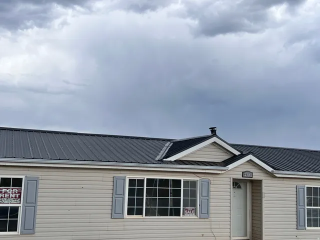 Exterior with light-toned siding, grey metal roofing, and multiple windows featuring grey shutters