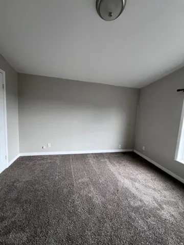 Neutral wall paint, plush carpet flooring, recessed window, and flush mount lighting