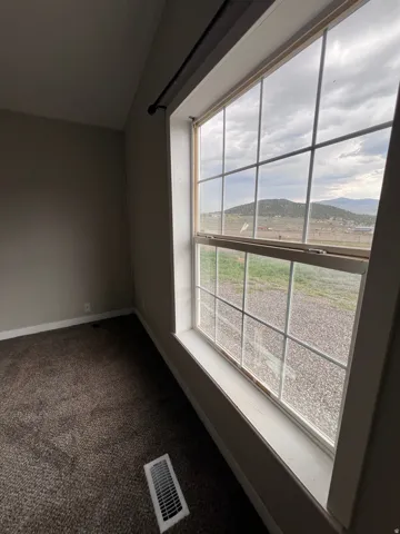 Window with grid panes and a deep sill, dark carpet flooring
