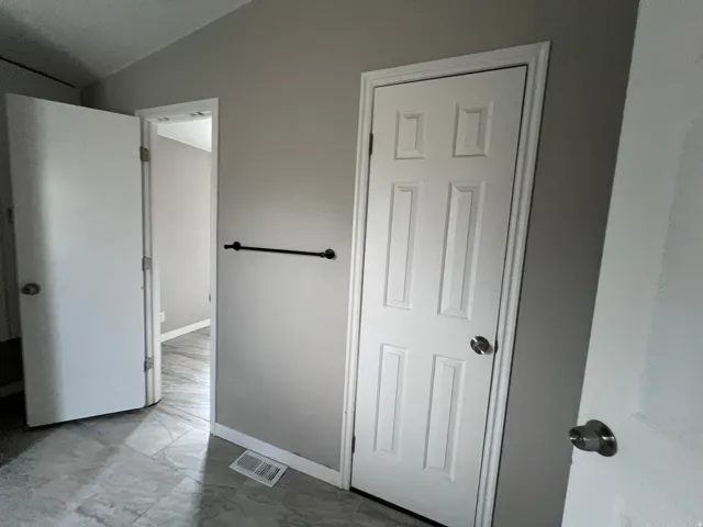 Tiled flooring with a neutral finish, white interior doors, and a matte black towel bar