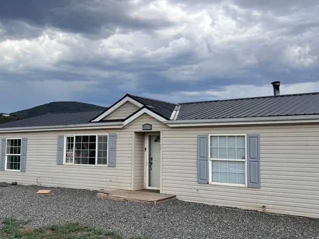 Light beige siding exterior with a dark grey metal roof