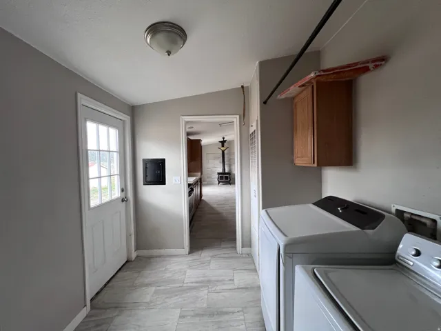 Laundry area featuring wood-finish cabinetry, light-toned walls, and wood-finish flooring