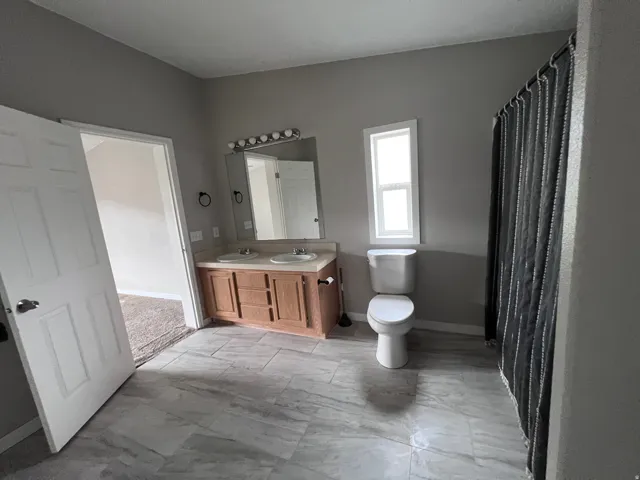 Dual vanity with integrated sinks, wood-finish cabinetry, and a framed mirror