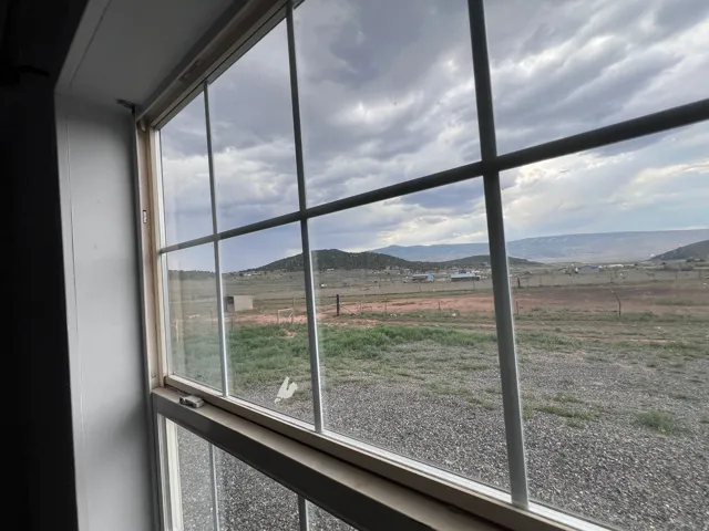 Window with muntins framing a mountain landscape and expansive open land