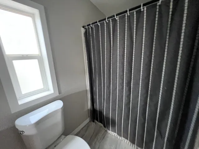 White two-pane window, white toilet, and wood-finish flooring