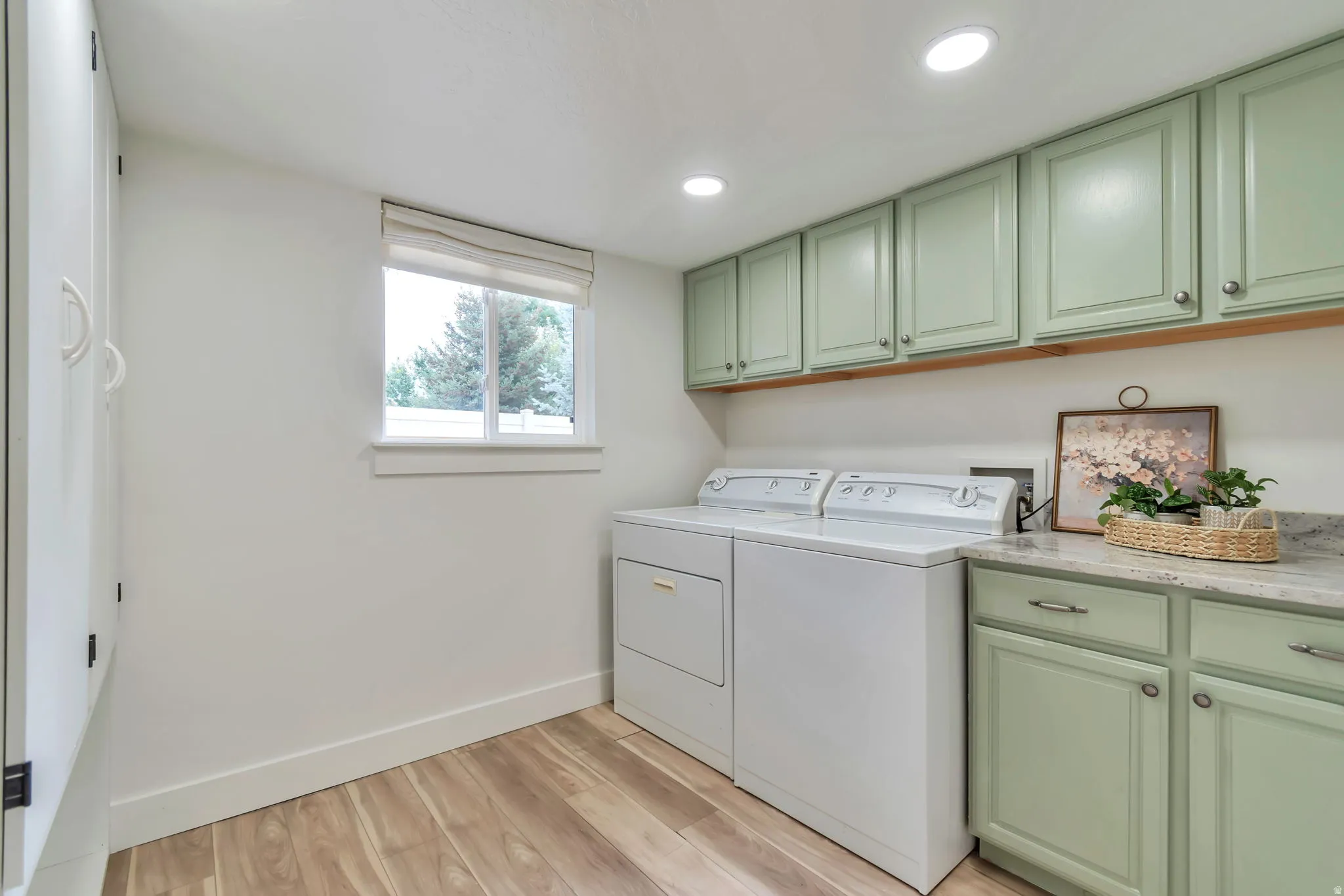 Utility room featuring wood-finish flooring, built-in cabinetry, and a window