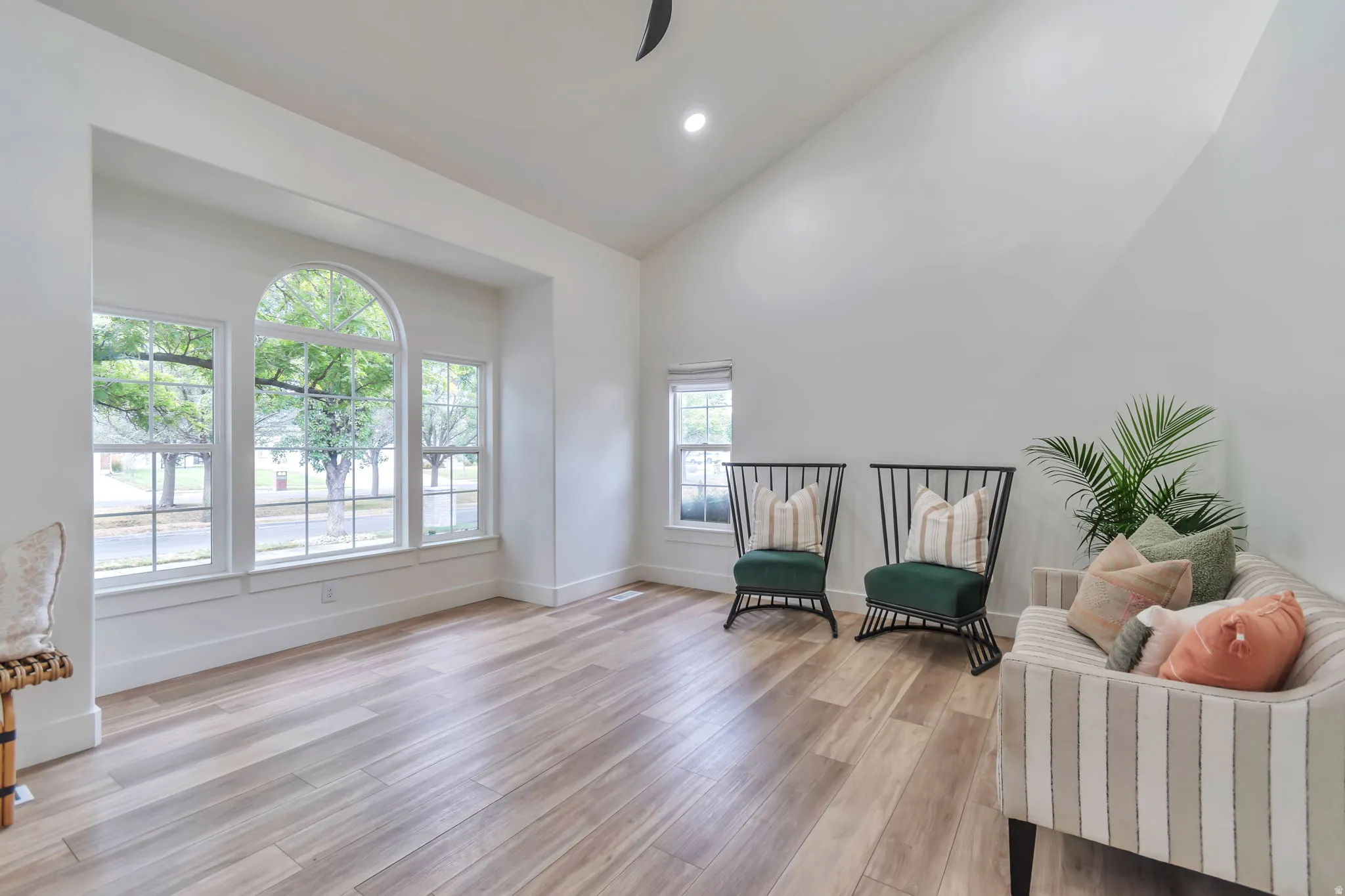 Vaulted ceiling with recessed lighting, wood-finish flooring, and white walls