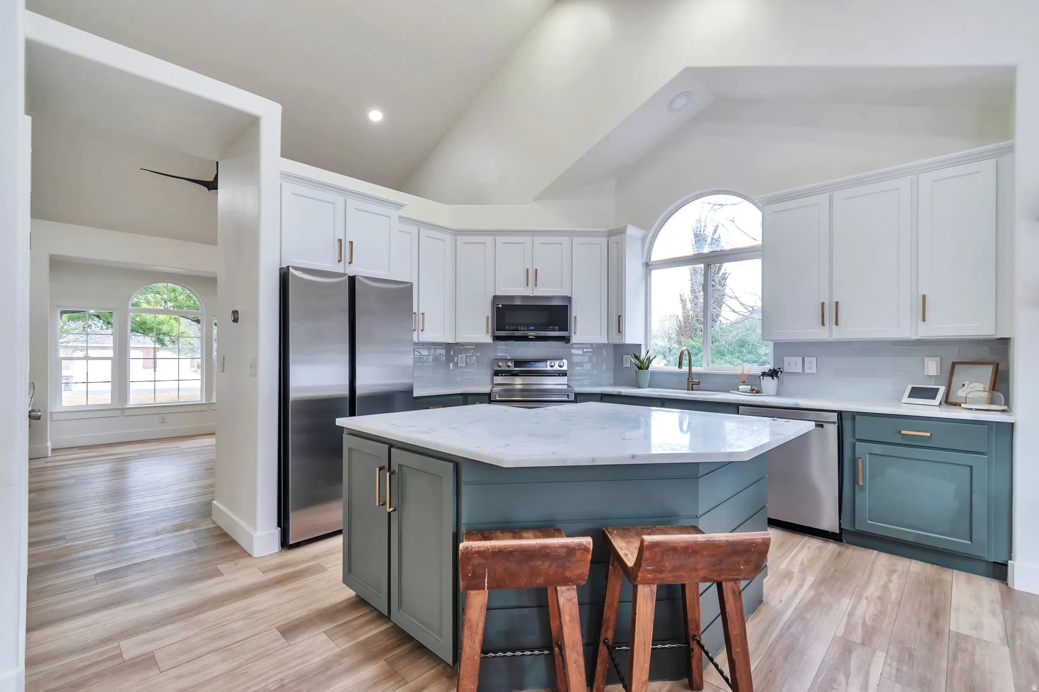 Vaulted ceiling kitchen featuring a hexagonal island with a stone countertop, two-tone cabinetry, and wood-finish flooring