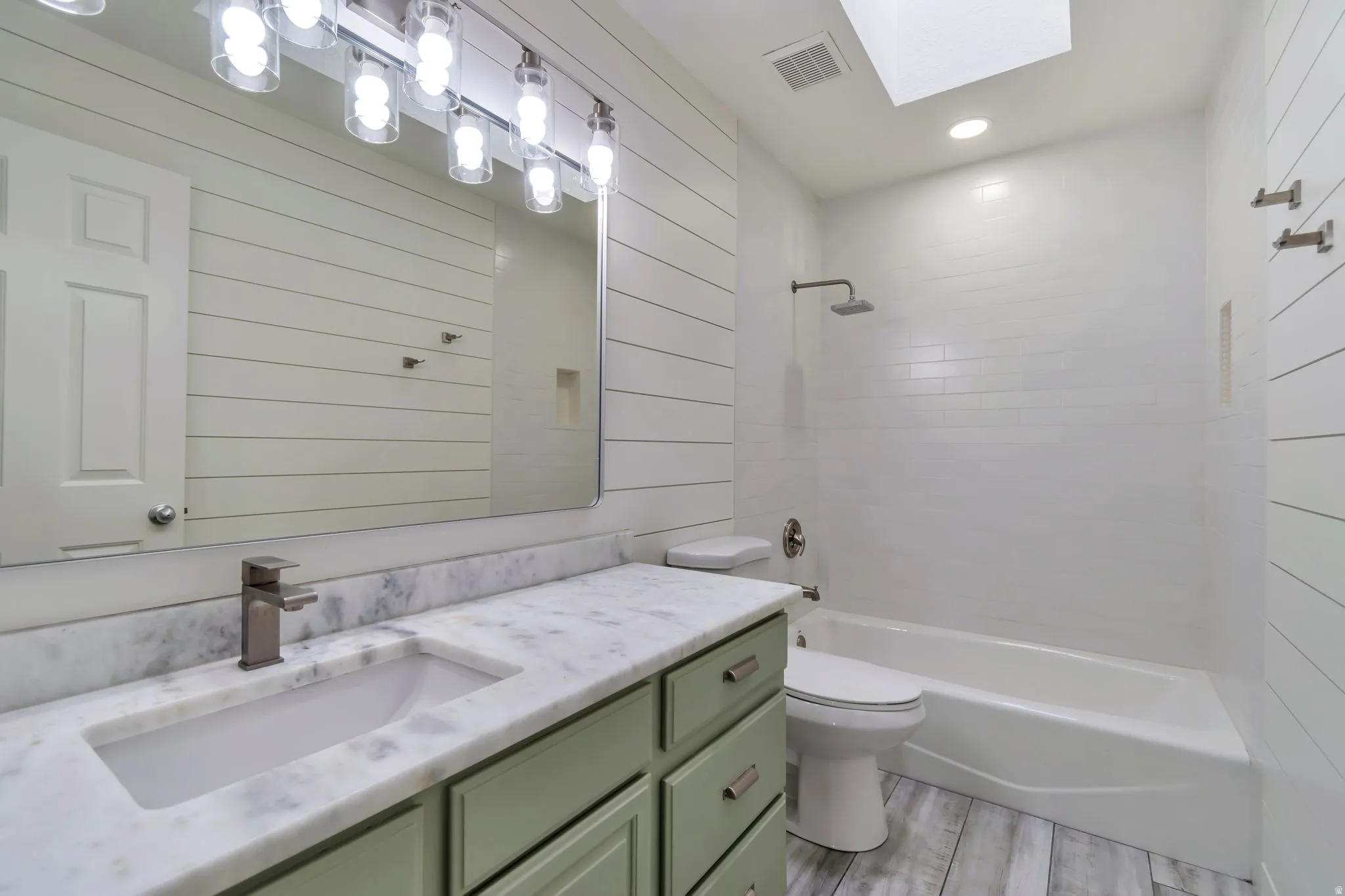 Bathroom featuring a single vanity with stone countertop, undermount sink, and sage green cabinetry