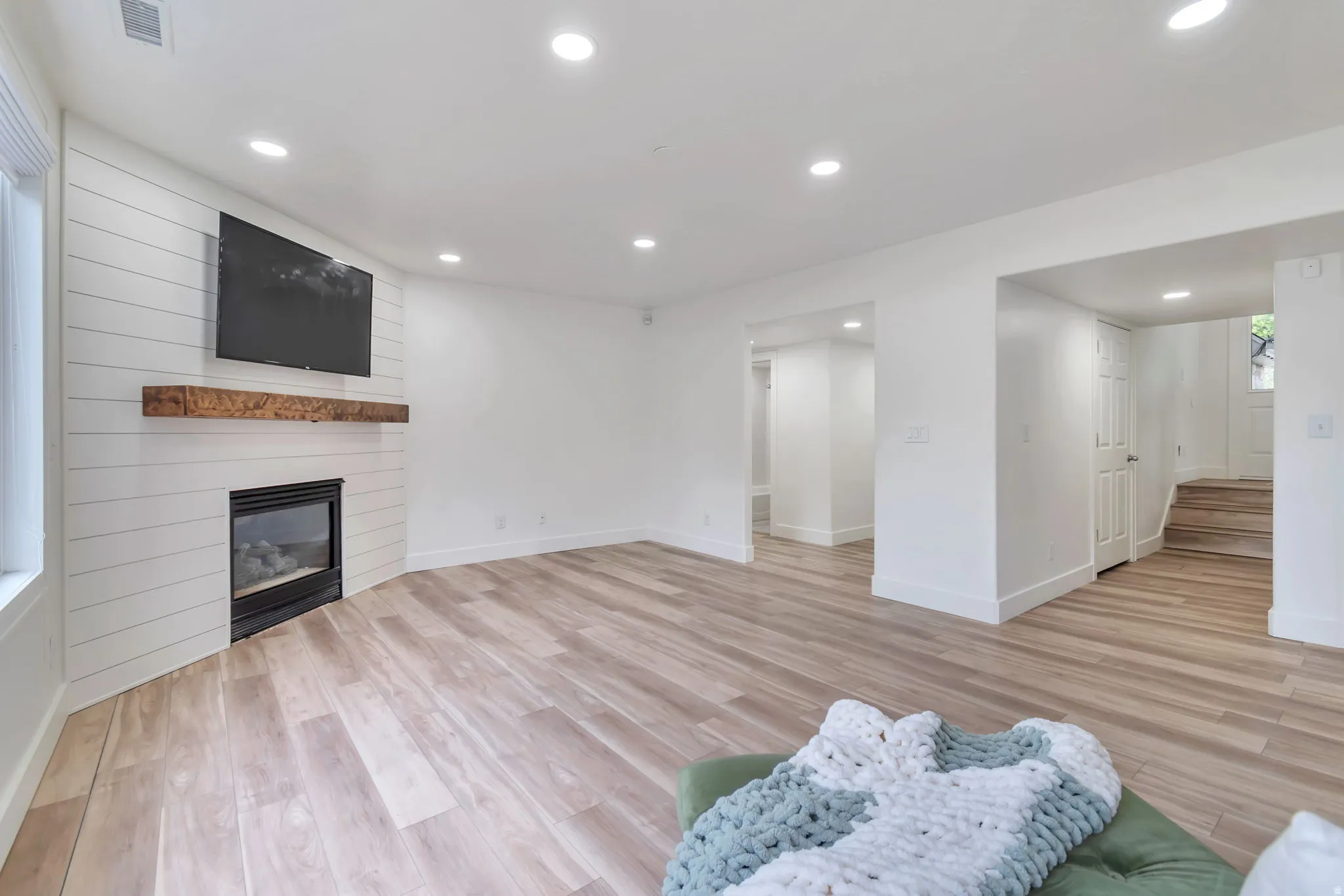 Recessed lighting illuminates wood-finish flooring throughout