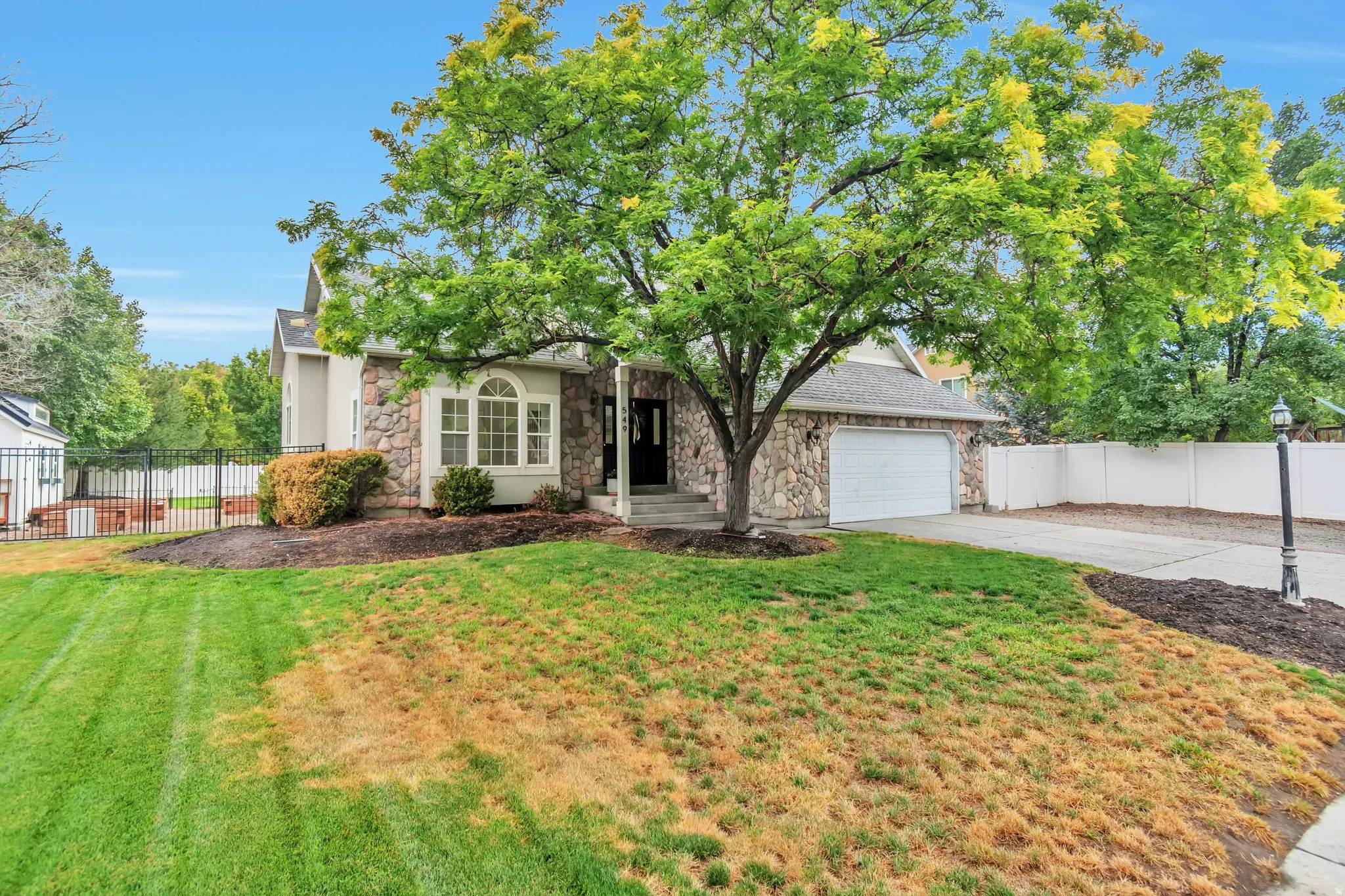 Stone veneer exterior with an attached garage, bay window, and covered entry