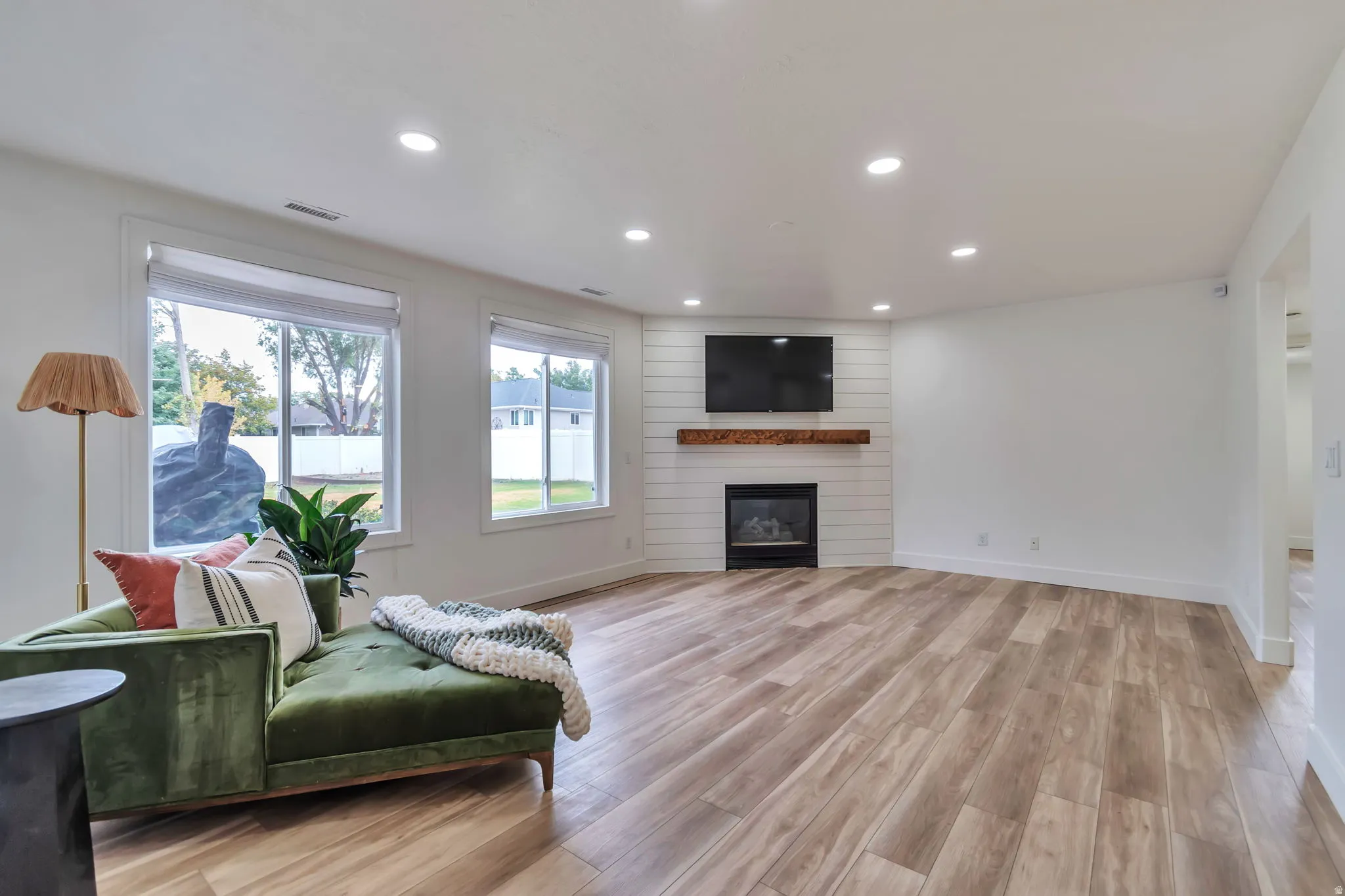 Recessed lighting, wood-finish flooring, a contemporary fireplace with a wood mantle, and multiple windows