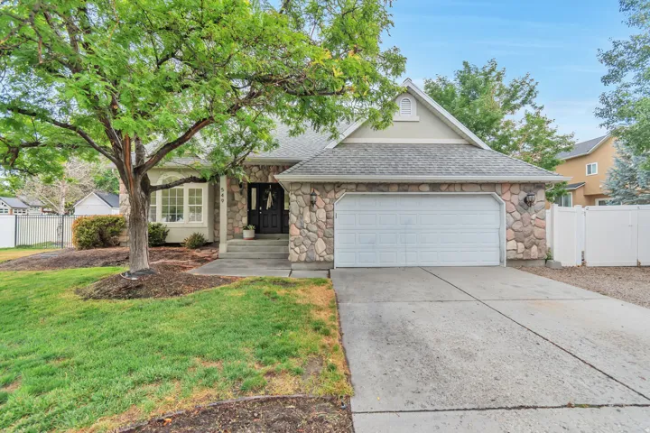 Stone veneer exterior with a concrete driveway, two-car garage, and a lush front lawn