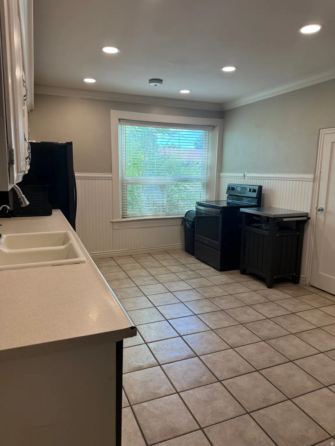 Kitchen featuring tile flooring, wainscoting, recessed lighting, and a double basin sink with an integrated countertop