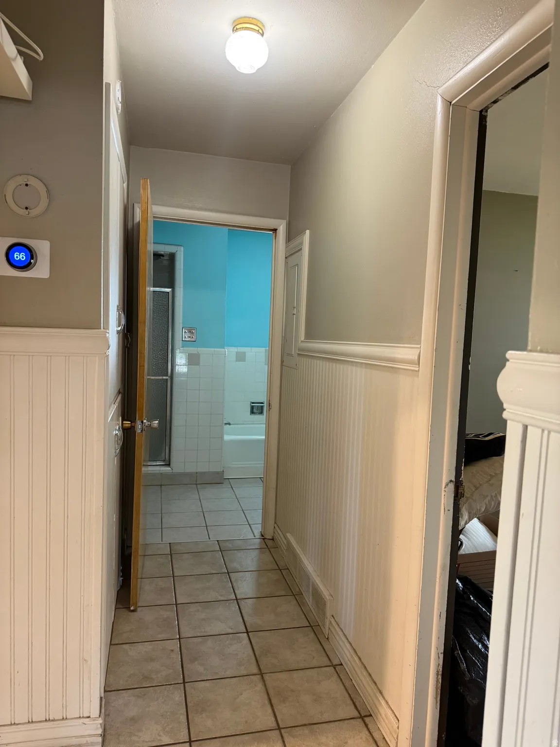 Hallway featuring tile flooring, wainscoting, and a ceiling-mounted light fixture