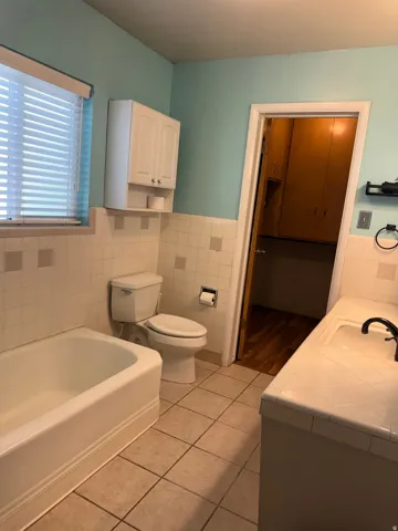 Bathroom featuring a built-in tub, tiled flooring, vanity with integrated sink, and overhead cabinetry