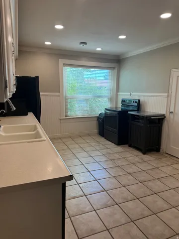 Kitchen featuring tile flooring, wainscoting, recessed lighting, and a double basin sink with an integrated countertop