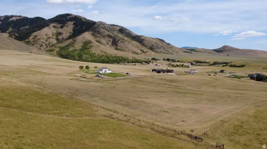 Expansive property with a white two-story residence, a large barn, and surrounding undeveloped land