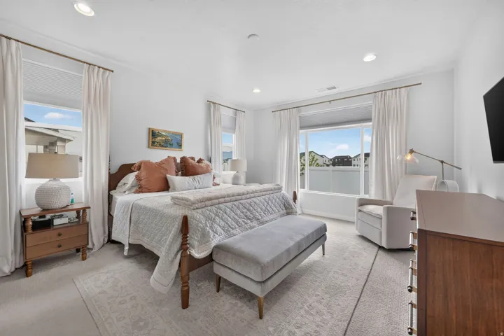 Recessed lighting illuminates the room, featuring two large windows with installed blinds and curtain rods