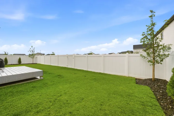 Manicured lawn with a white privacy fence and a composite material deck