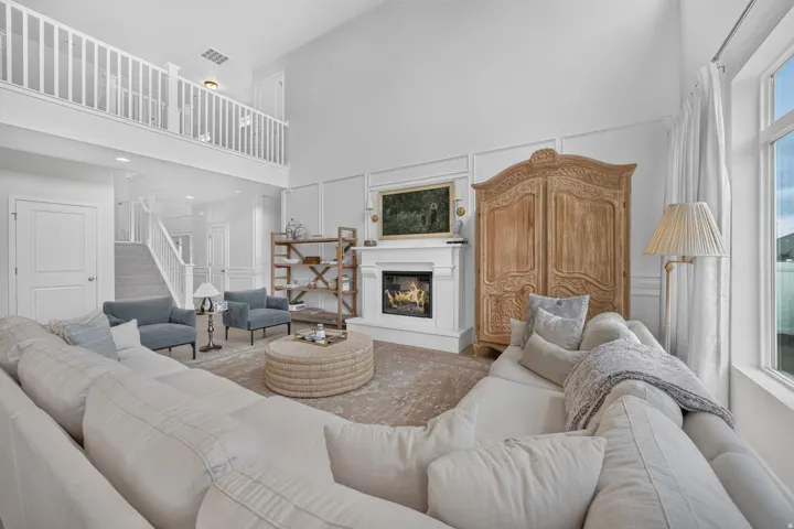Vaulted ceiling with a second-story landing, fireplace with a mantel, and decorative wall paneling