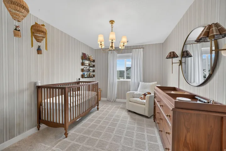Patterned wall covering, ceiling-mounted chandelier, window with white curtains, wall-mounted shelving, and geometric pattern carpet