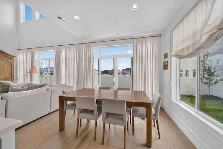 Vaulted ceiling with transom windows, recessed lighting, expansive glass sliding door, and wood-finish flooring
