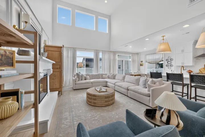 Vaulted ceilings with high windows, built-in fireplace, recessed lighting, wood-finish flooring, and a kitchen island with seating